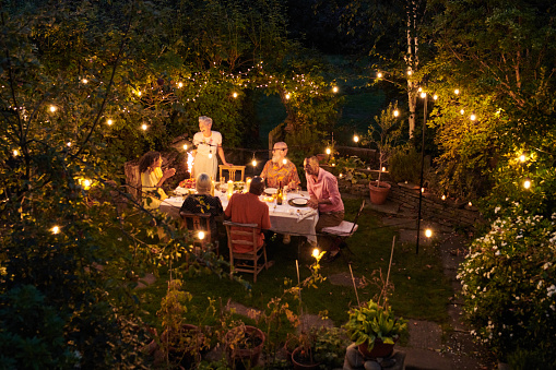 Freunde und Familie sitzen am Tisch und genießen einen schönen Sommerabend.
